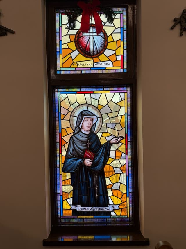 Full stained glass window of St. Faustyna Kowalska with Sacred Heart above