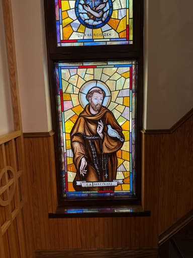 Stained glass window of St. Francis of Assisi in Franciscan habit with a dove